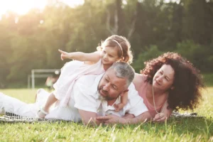 A happy family, consisting of a father, mother, and daughter, enjoys a sunny day outdoors, demonstrating the peace of mind that comes with reducing dental expenses through the Rubicare Dental Savings Plan.
