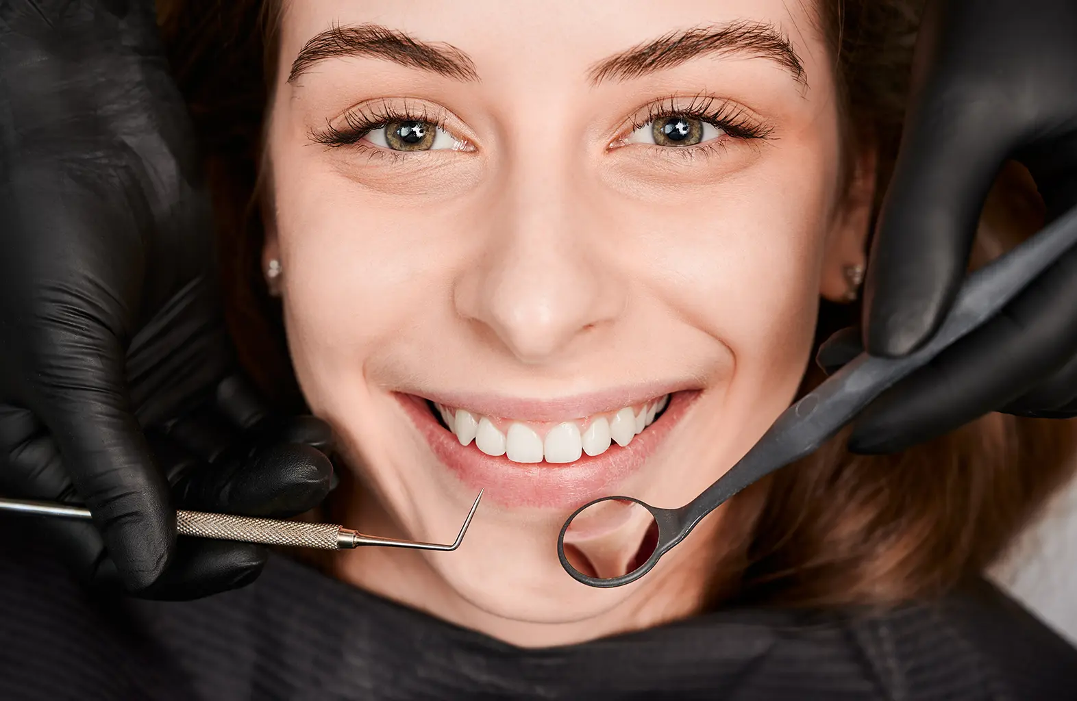 A cheerful young woman receives a dental examination, highlighting the importance of dental fillings and the cost-saving benefits of Rubicare Health Savings Plans.