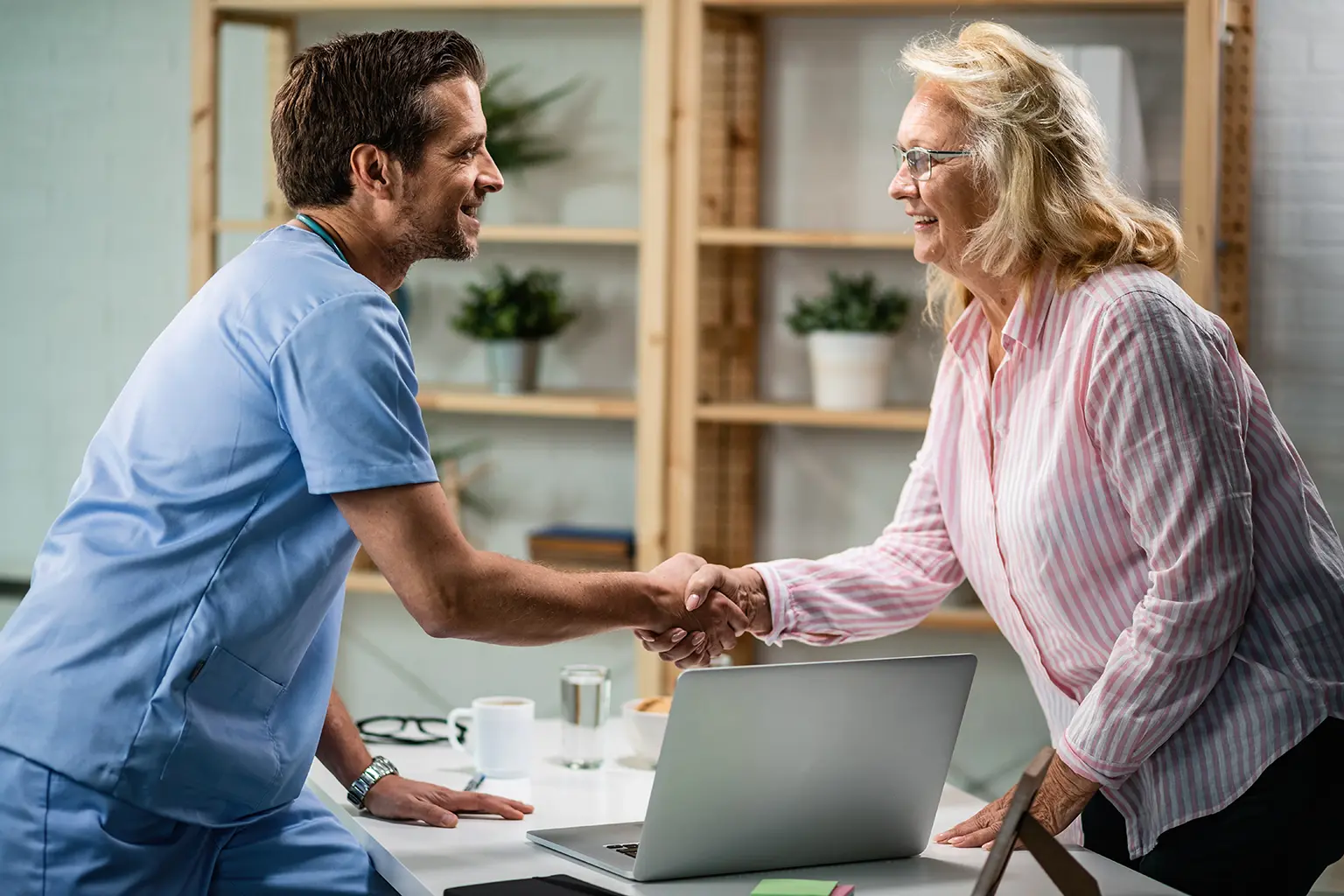 Smiling doctor and senior woman shaking hands in a healthcare setting, representing personalized service and care with Rubicare Health Savings Plan – discover why Rubicare is trusted by local communities.