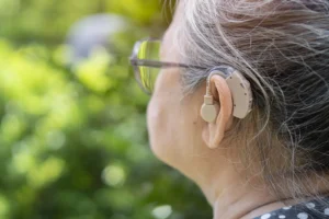 Middle-aged woman wearing a hearing aid as part of her hearing aid fitting process, supported by Rubicare’s health savings plan.